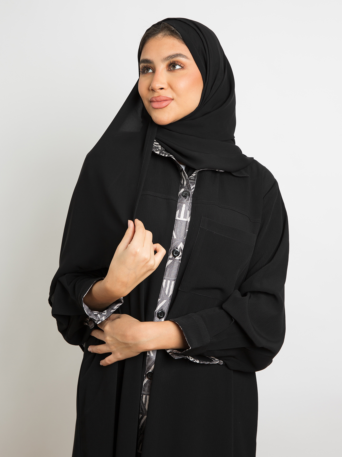 Open long black shirt abaya in fancy yoryu fabric with artistic ornament and buttons all the way down to the knee by kaafmeem